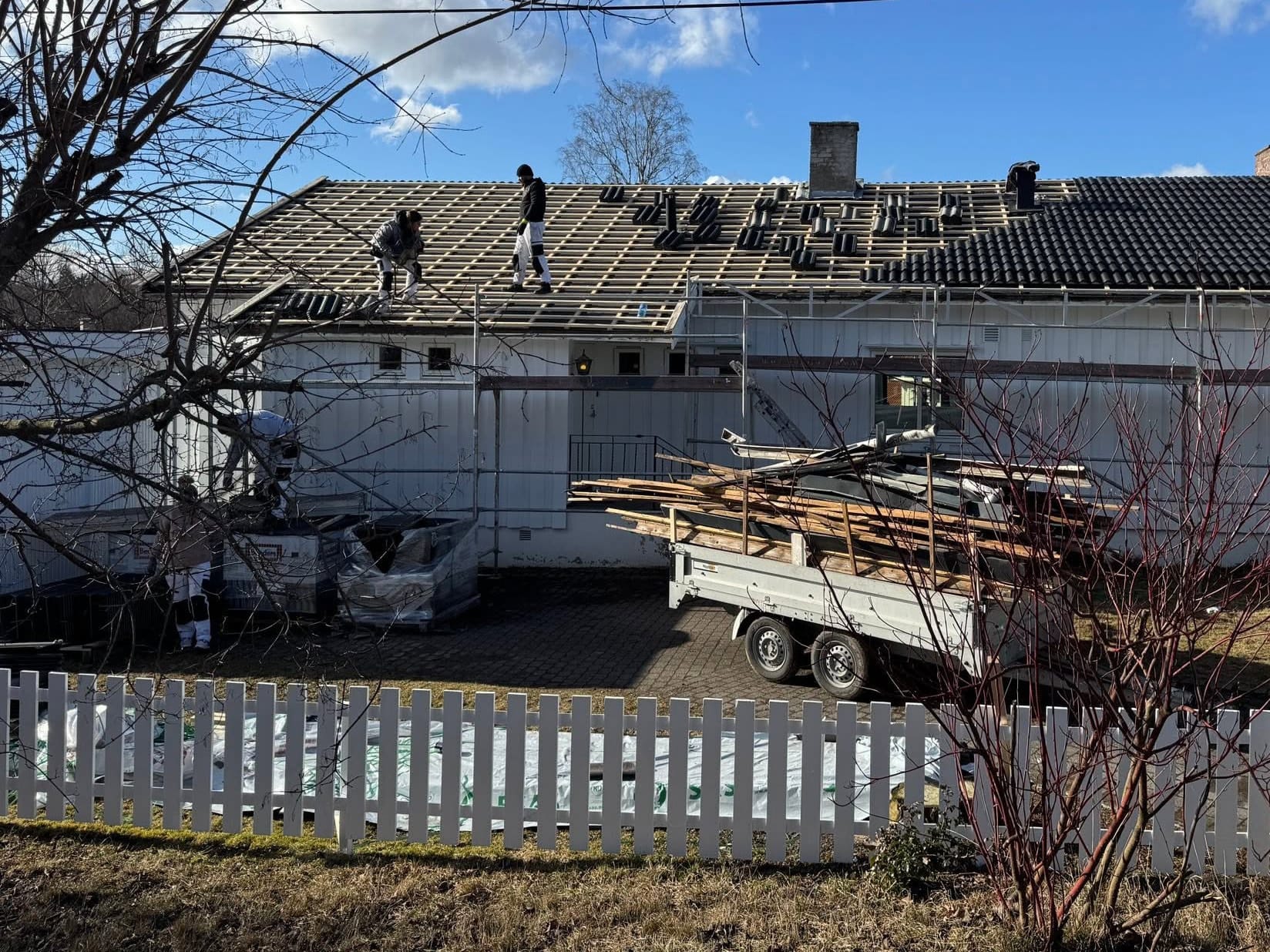 Taktekkerne legger ny stein. Den ene halvdelen av taket er ferdig lagt.